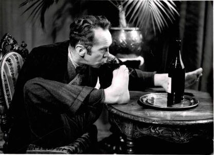 Press photograph of Charles Pasche drinking a glass of red wine with is foot
