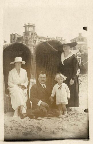 Four people posing in front of two beach chairs. - undated