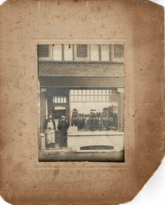 Two men posing in front of an umbrella shop. - no date